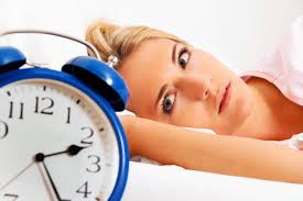 Woman with Insomnia lying in bed starring at Clock